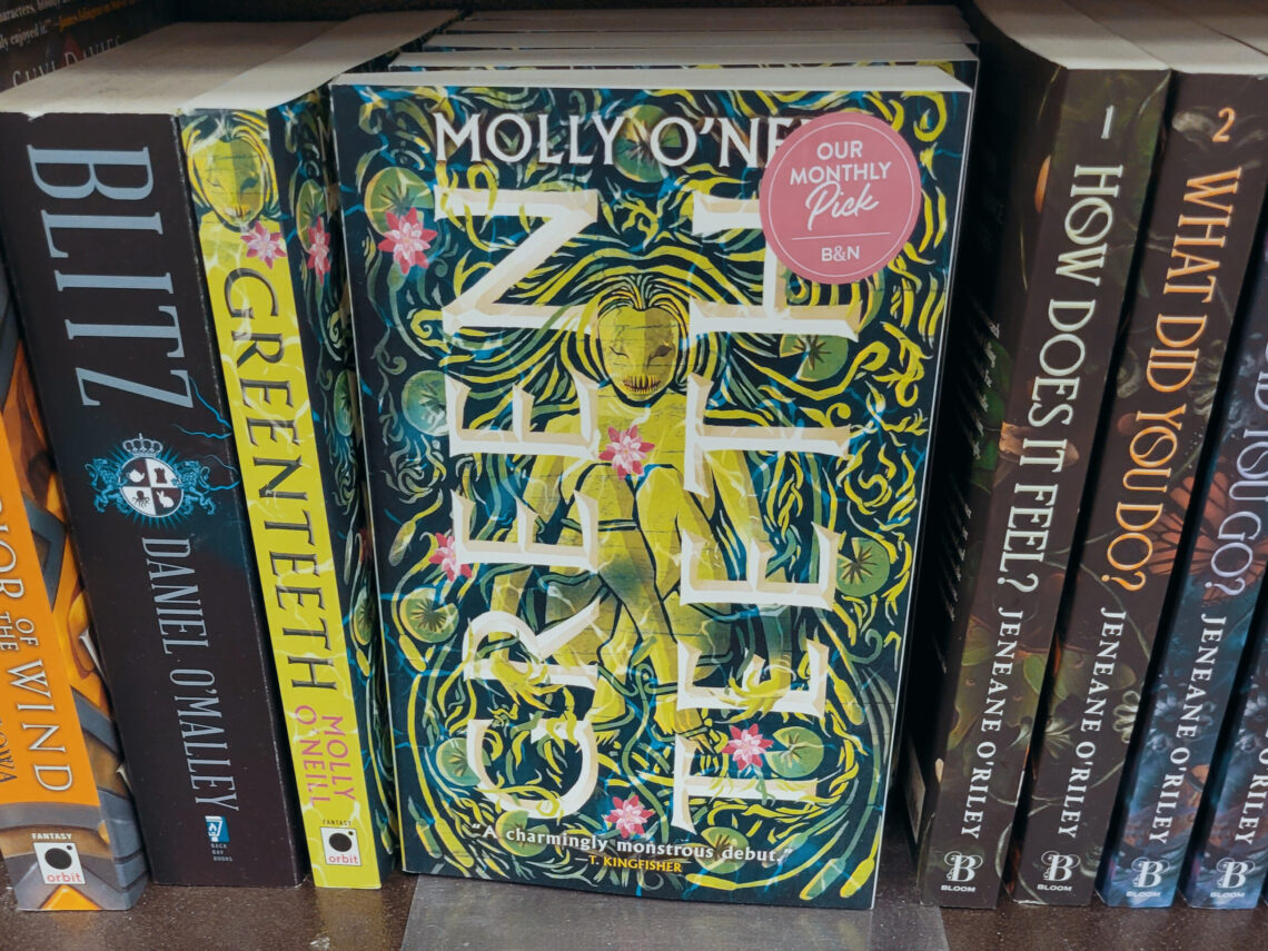 The cover of "Greenteeth" by Molly O'Neill featured on a shelf of books at a bookstore.
